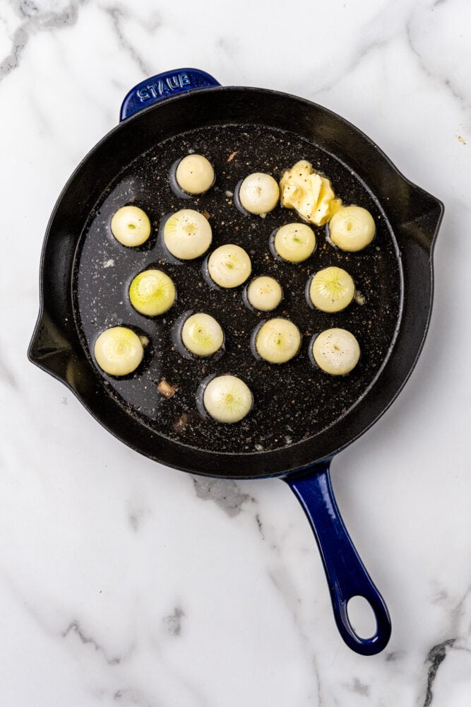 cooking whole boiler onions in a blue Staub skillet