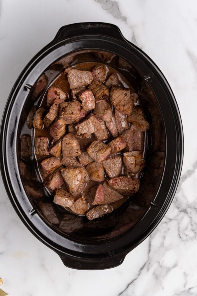 browned beef and red wine in a slow cooker