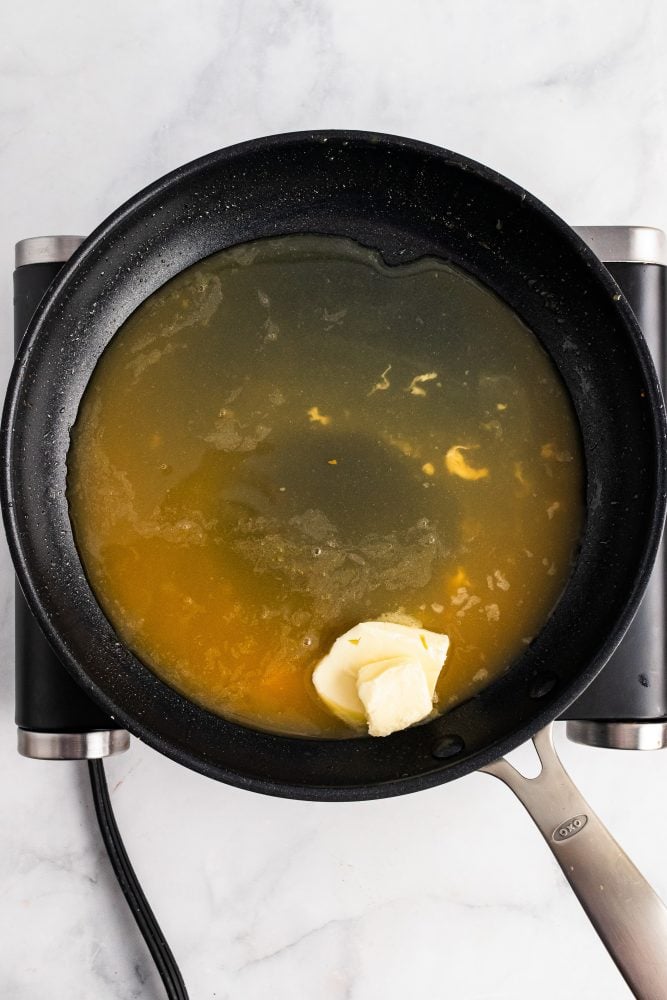Adding butter to frying pan with apple cider to create dressing for salad