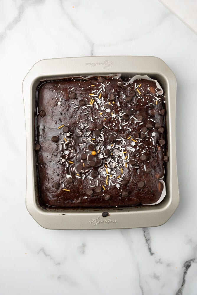 mocha brownies in square baking pan, topped with white and gold candy sprinkles and chocolate chips