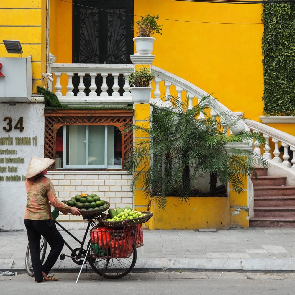 Woman selling fruit in front of a yellow home