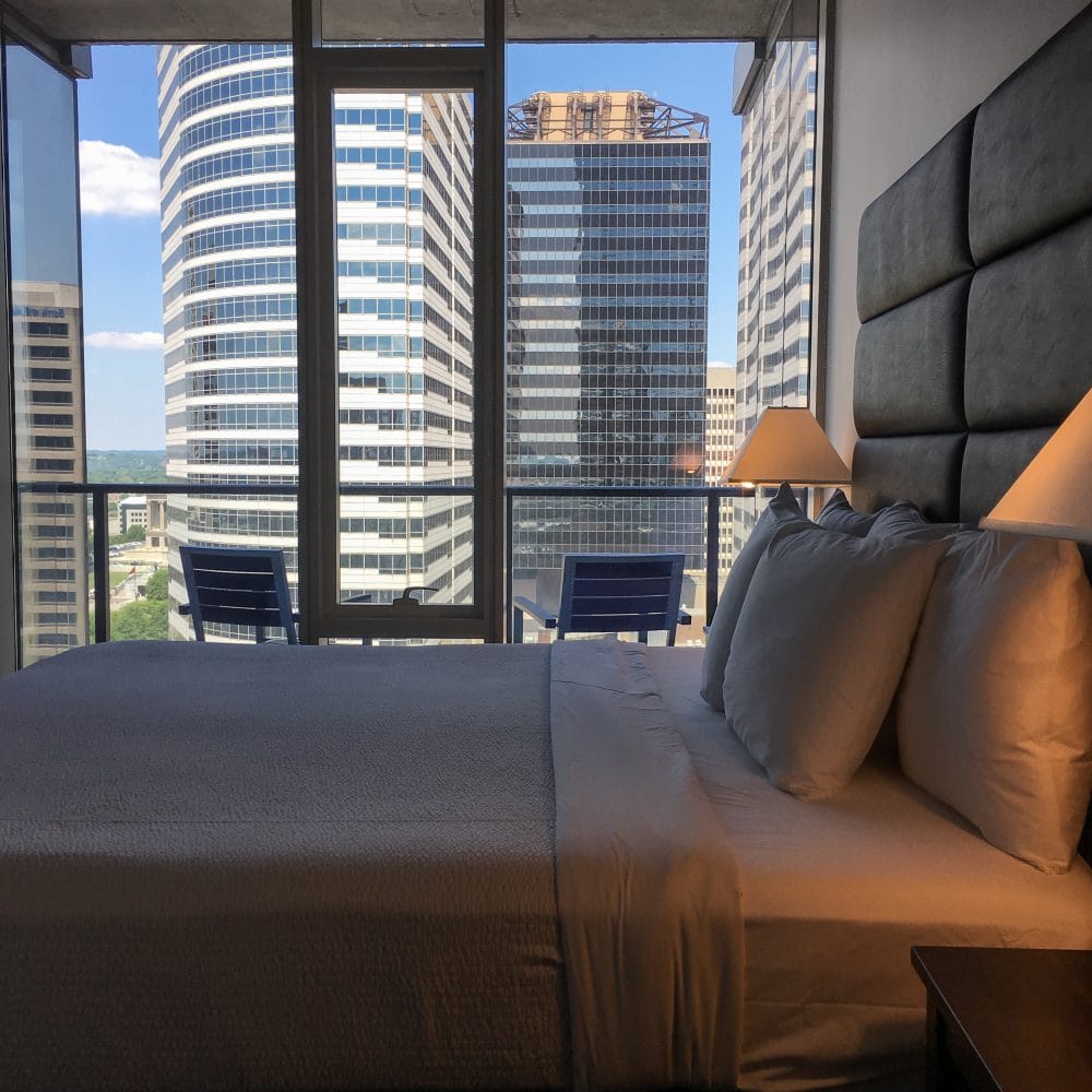 View of bedroom and balcony looking out at skyscraper office buildings in Nashville from AirBnB room.