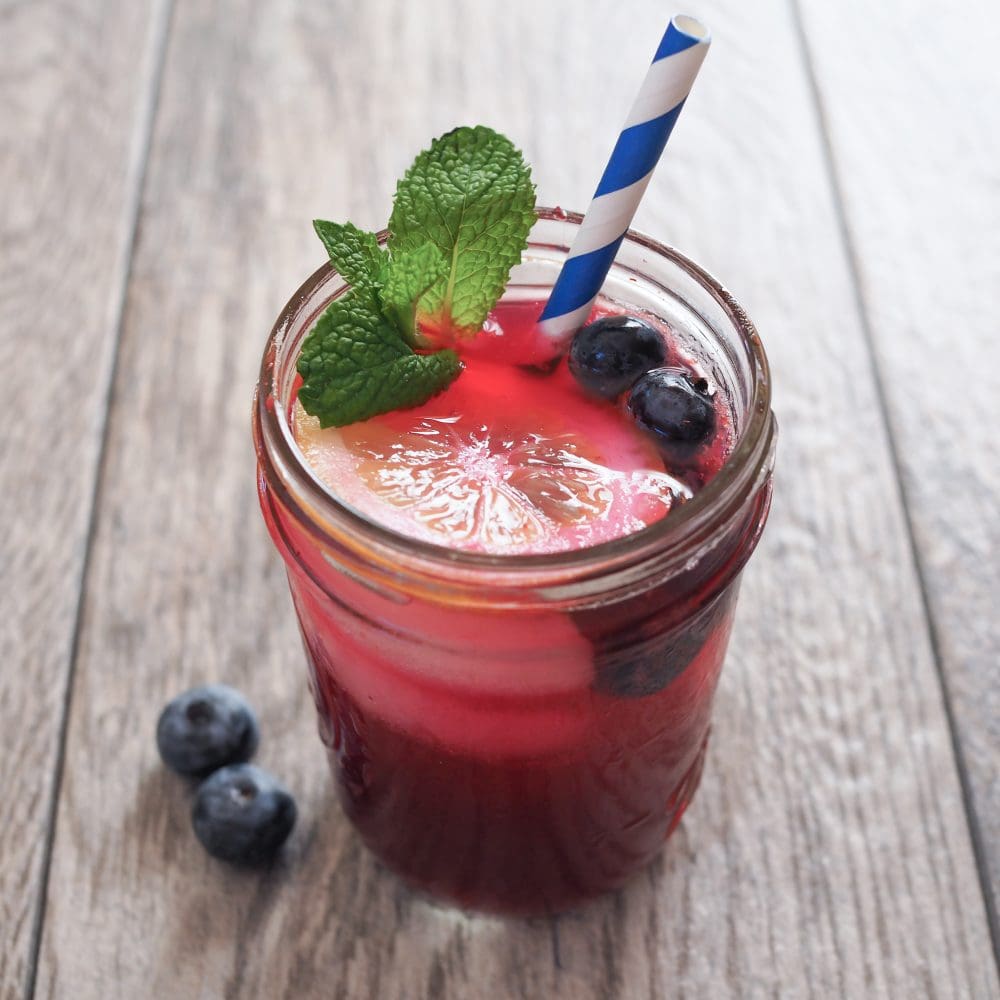 Sparkling Blueberry Lemonade With Blue Striped Straw And Mint
