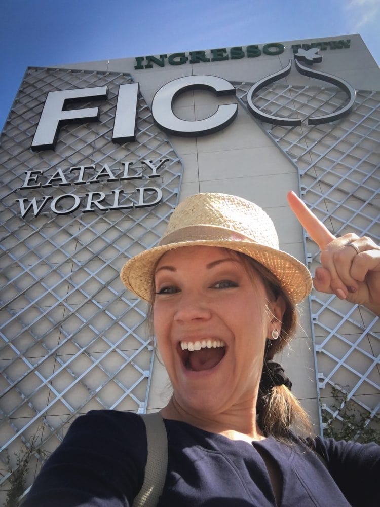 Rachelle Lucas of TheTravelBite.com standing in front of the sign for FICO Eataly World.