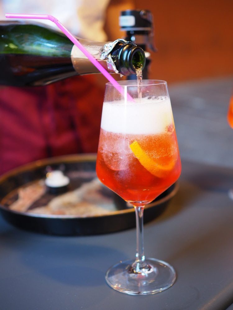 The classic bubbly orange Aperol Spritz cocktail being topped off with Prosecco. 