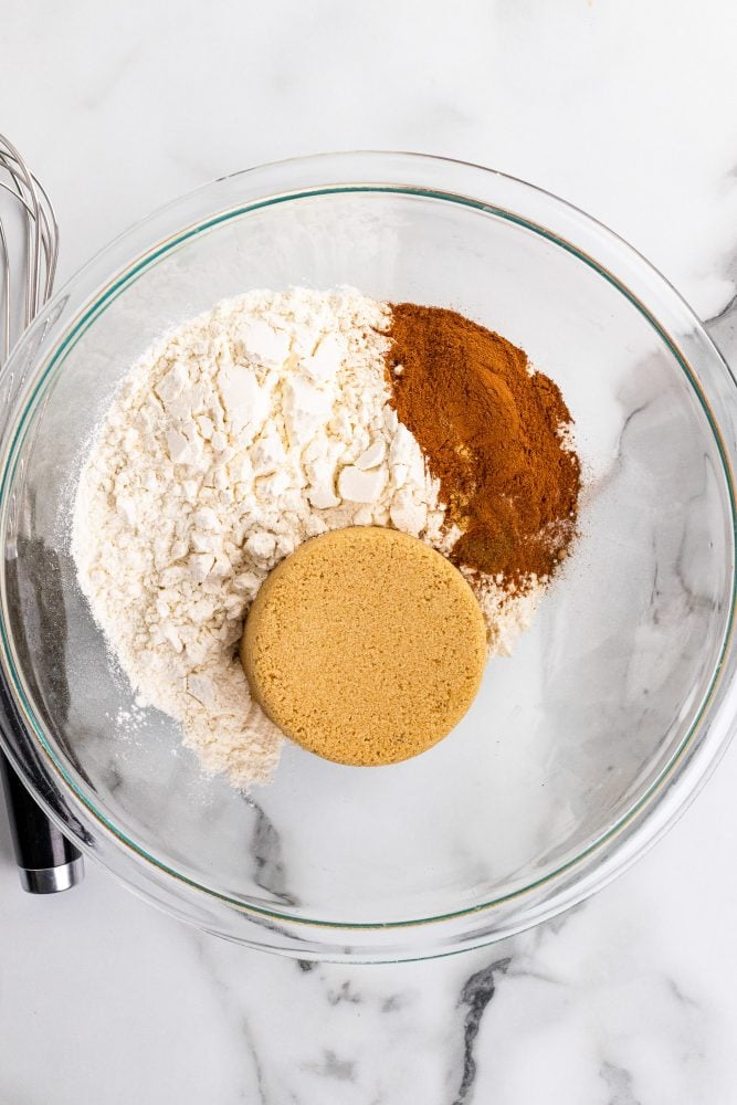 Flour, brown sugar, and spices in a clear glass bowl.