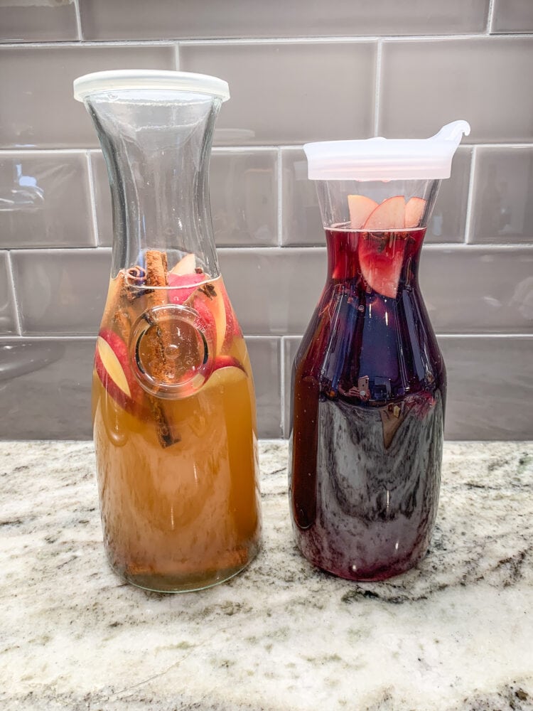 Two carafes filled with fall sangria, one with white wine, one with red wine.
