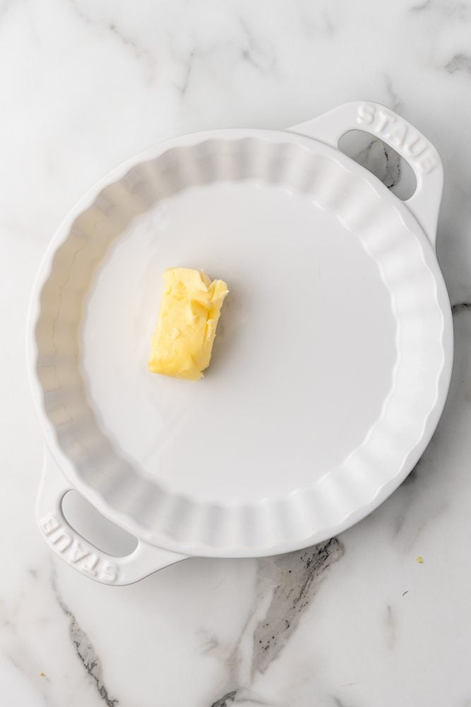 1/4 stick of butter in a white Staub pie dish.