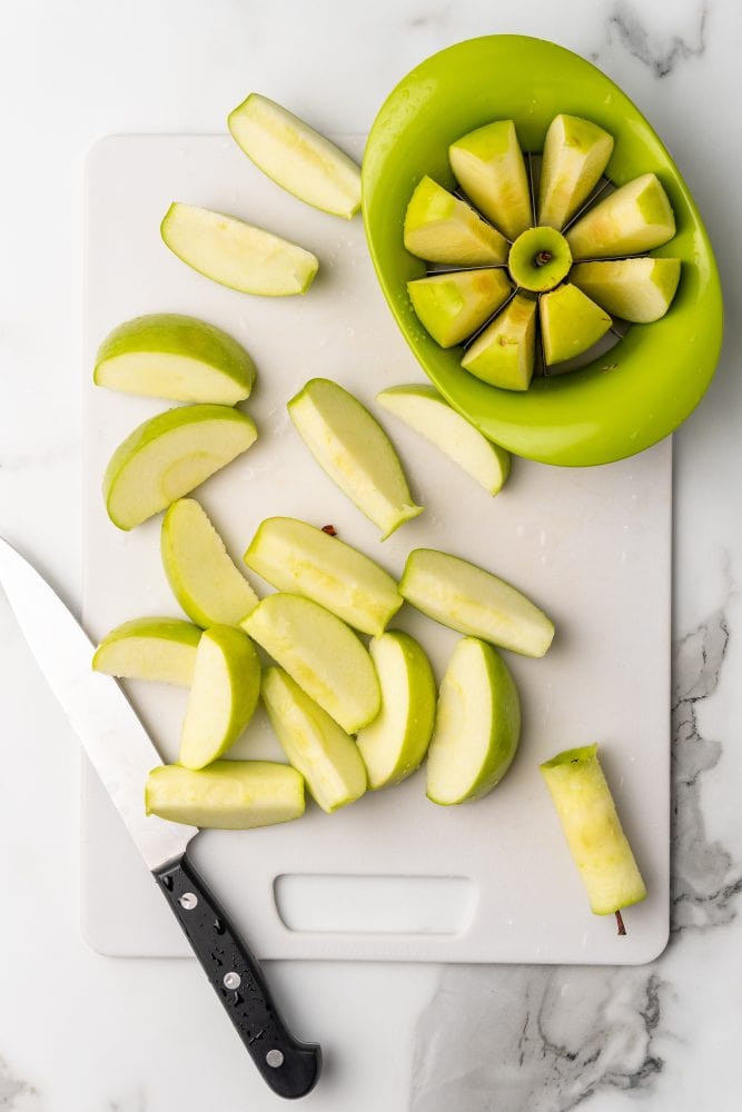 Chopping green apples on a white cutting board.