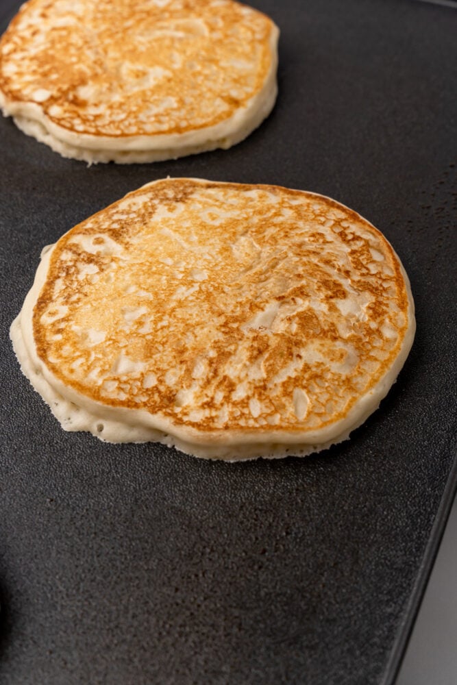 Closeup of golden brown fluffy pancake on a griddle.