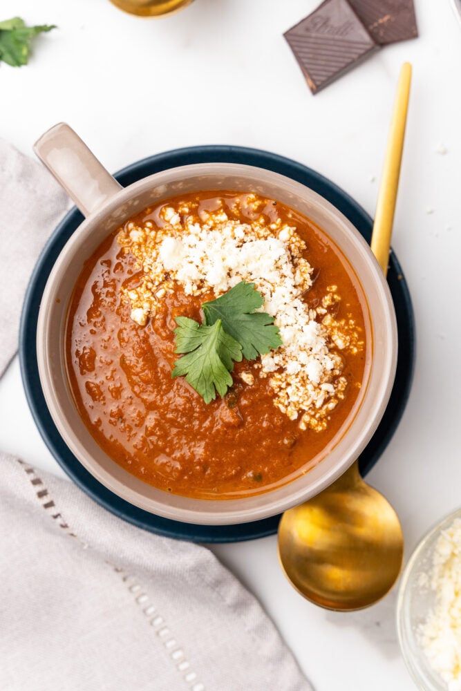 Overhead look at spicy tomato soup with crumbled cheese and parsely.