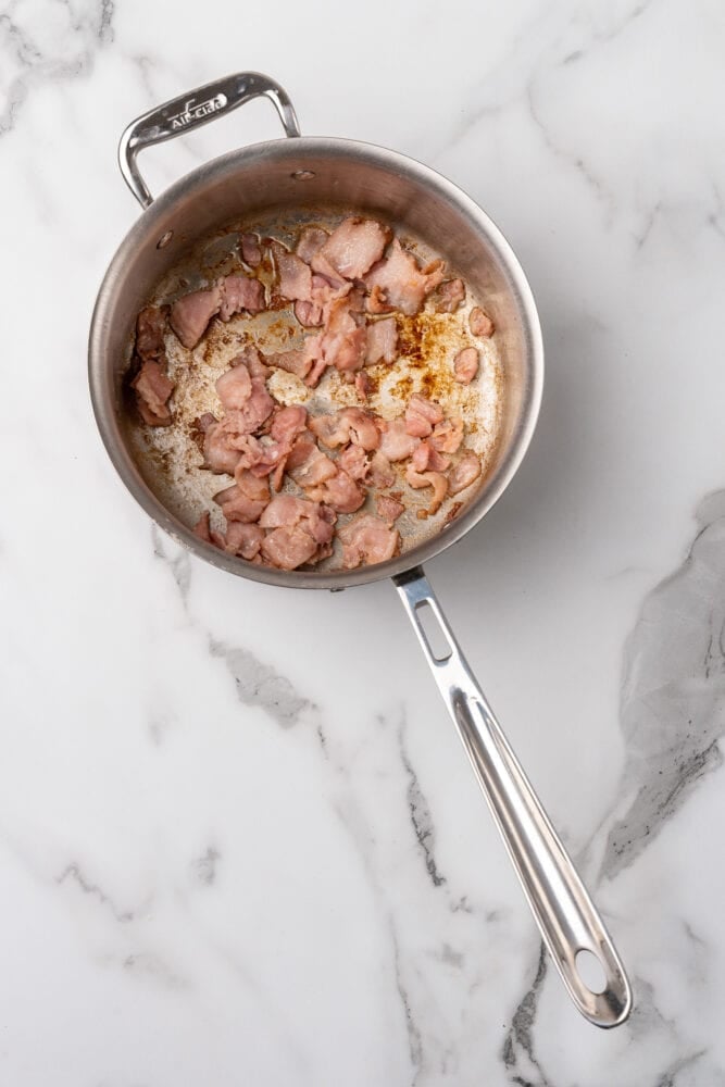 Browned bacon in a stainless steel soup pan.