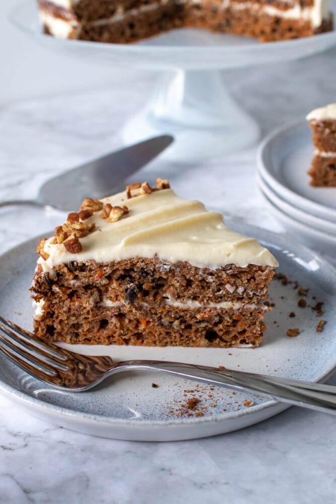 Slice of gluten free carrot cake on a serving plate with a fork.