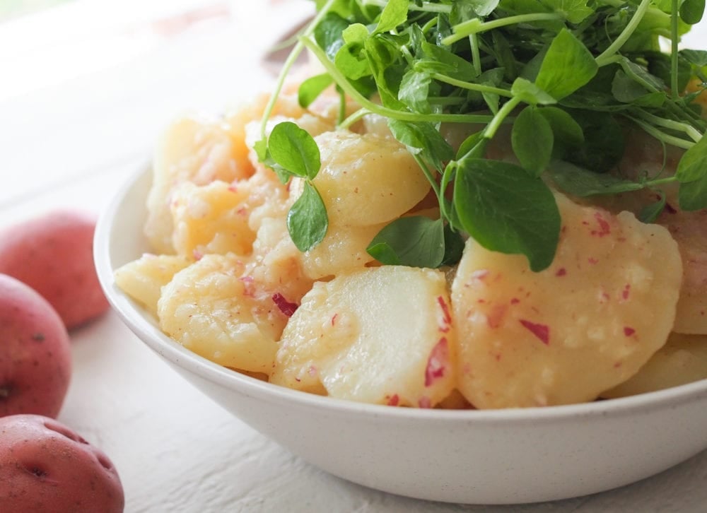 Side angle of potato salad topped with marche lettuce.