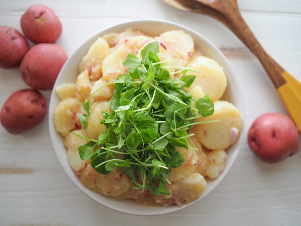 Overhead shot of Austrian style potato salad topped with greens.