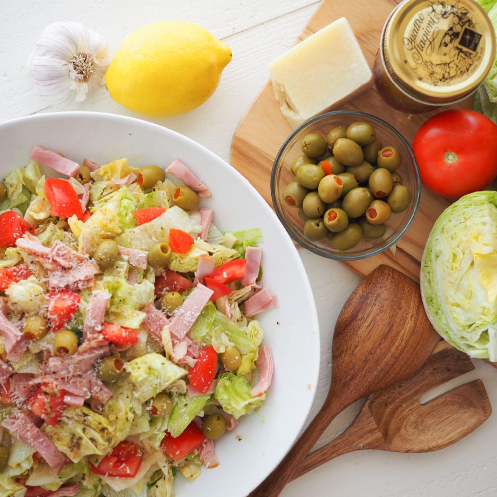 Overhead look at a big bowl of the 1905 salad with romaine lettuce, cubes of ham, Spanish olives, diced tomatoes, and grated parmesan cheese.