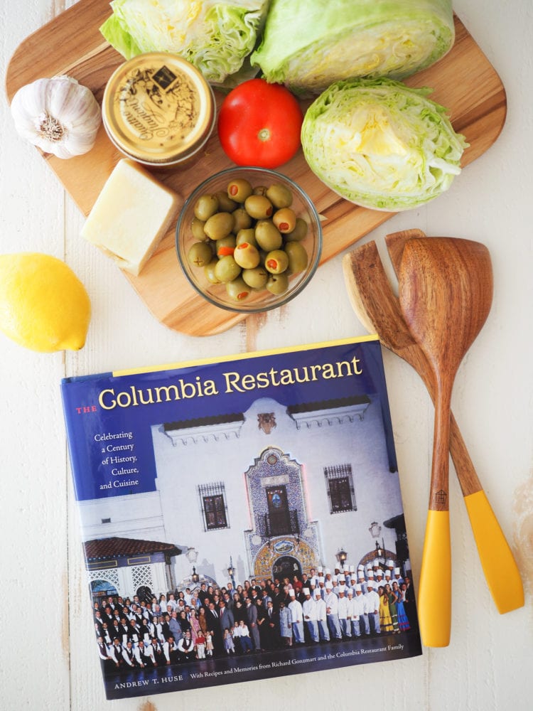 A picture of the Columbia Restaurant cookbook with a cutting board holding the ingredients.