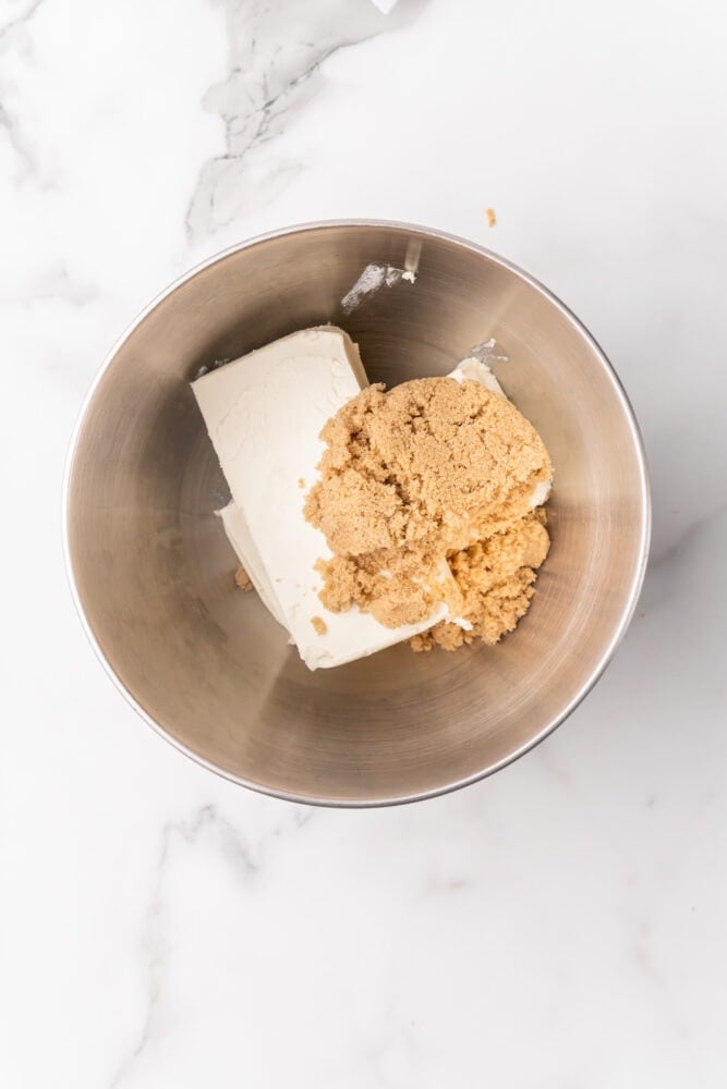 Cream cheese and brown sugar in a stainless steel bowl.