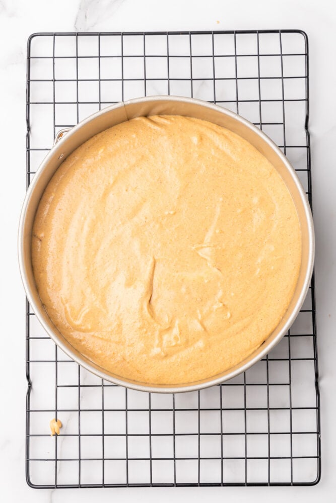 Pumpkin cheesecake filling spread on top of crust in spring form pan.