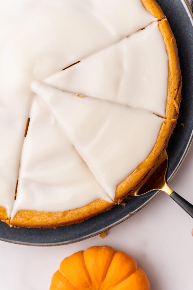 Triangular slices made into pumpkin cheesecake with a pie server reader to lift a slice.