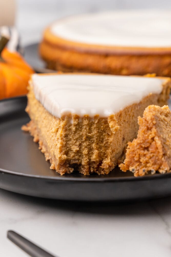 Close up of the front of a slice of pumpkin cheesecake, showing fork marks and texture.