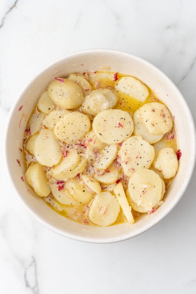 austian potato salad, garnished with fresh cracked black pepper, in a white bowl before serving.