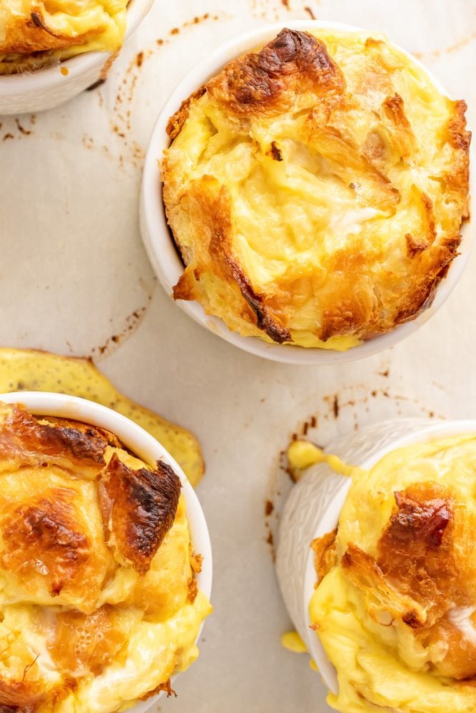 Fresh baked croissant bread puddings straight out of the oven. They're golden and crispy along the top, and the parchment paper has caught any batter that as spilled over the top.
