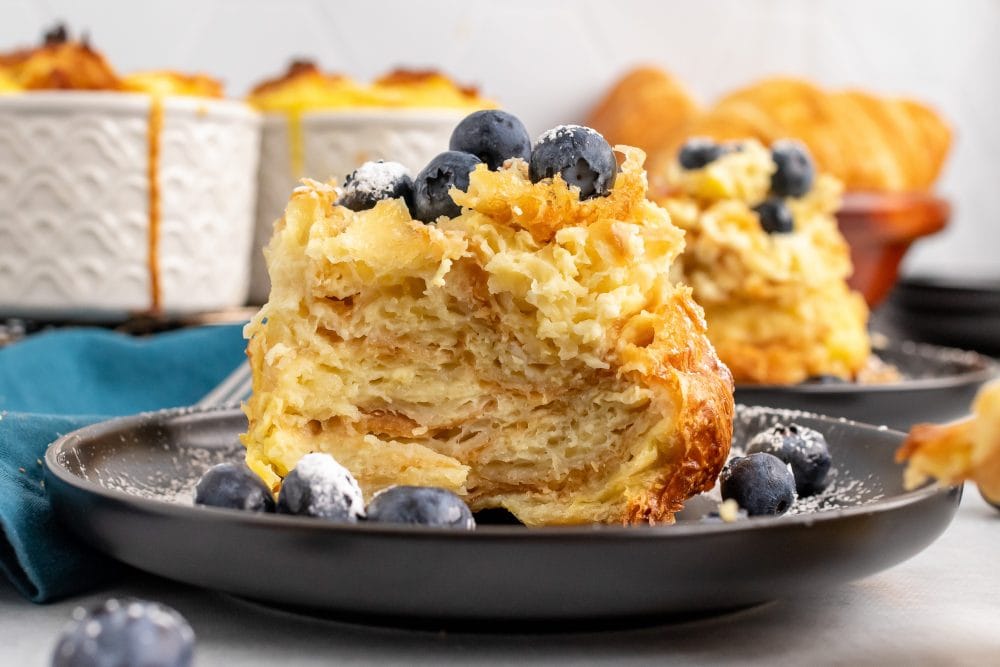 Side view of croissant bread pudding cut into to show the flaky layers of croissant.