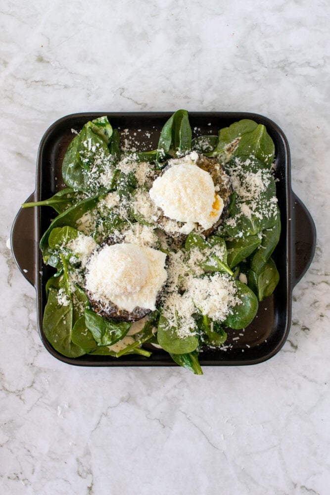 Overhead shot of eggs with parmesan over the portobello mushrooms, before broiling.