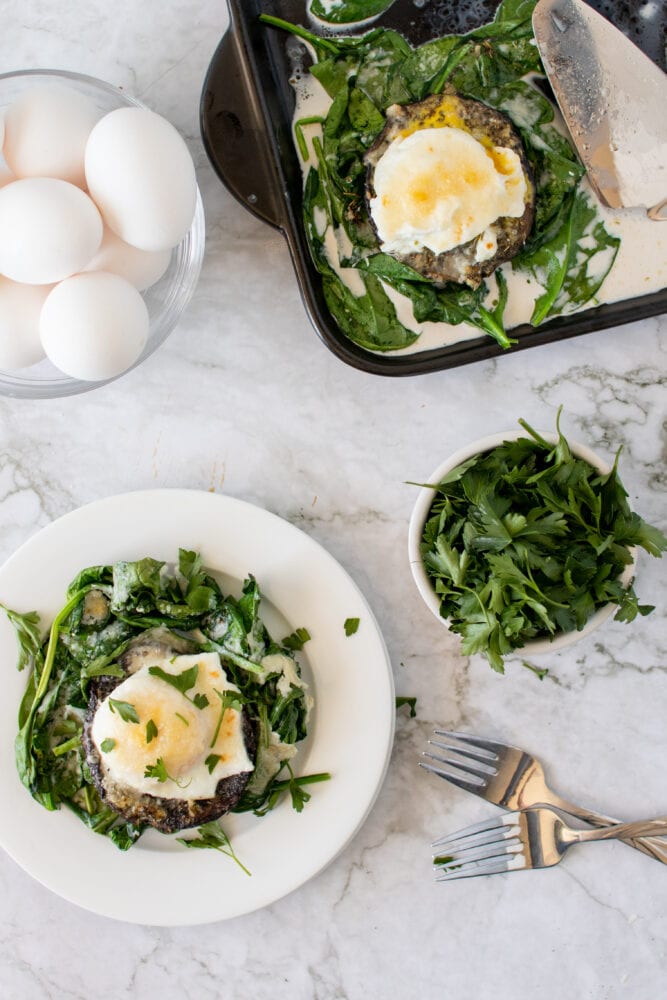 Overhead shot of eggs and baked portobello mushrooms on a bed of spinach