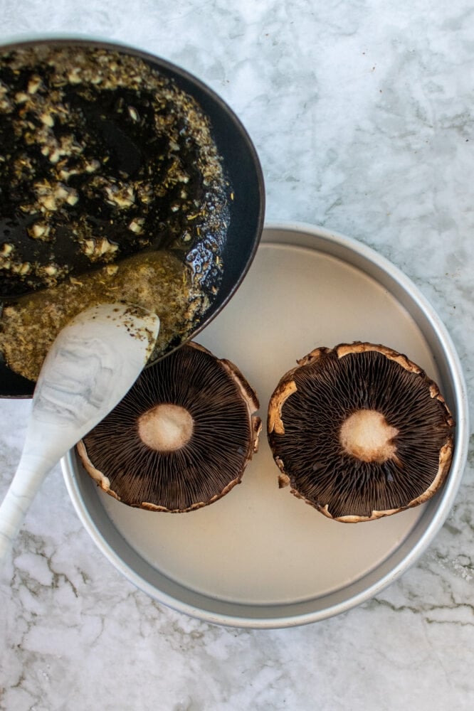 Overhead shot of pouring butter and Italian seasoning into mushroom caps.