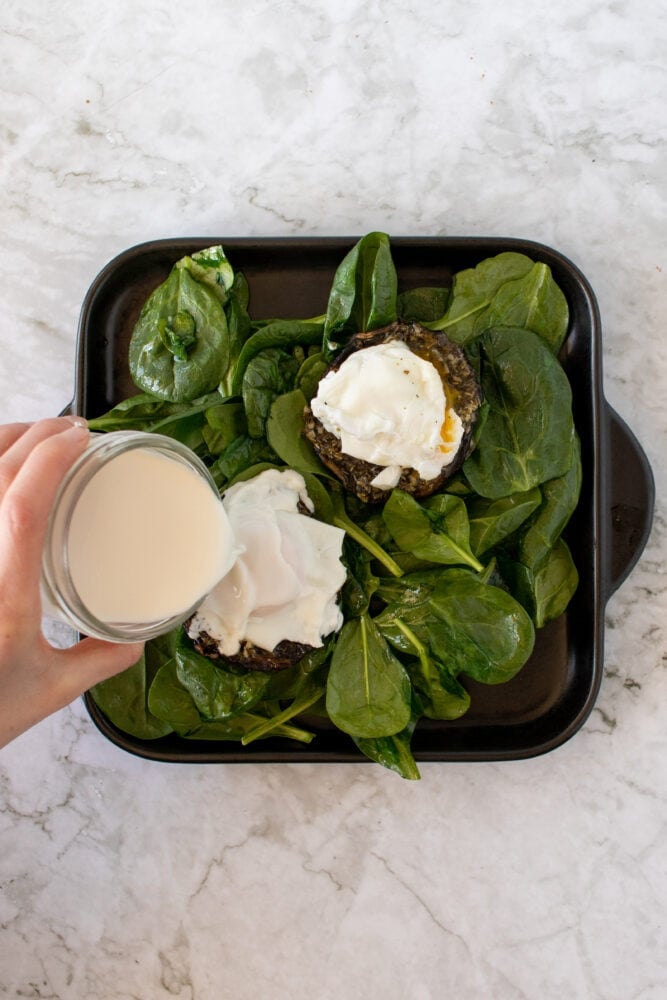 Pouring cream on top of egg and portobello mushrooms.