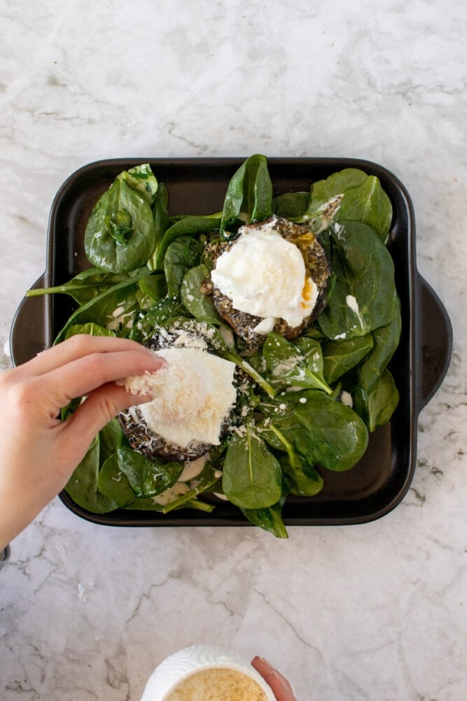 Overhead shot of sprinkling parmesan cheese onto mushrooms.