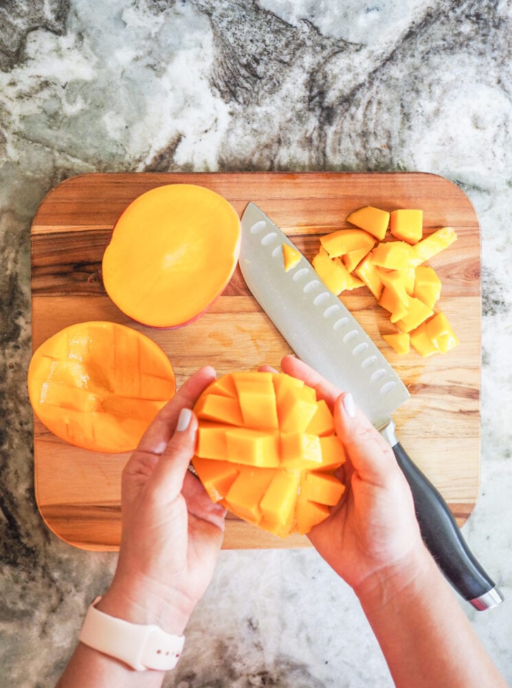 Overhead look at a sliced mango with the mango skin turned inside out so that the fruit is ready to be cut away.