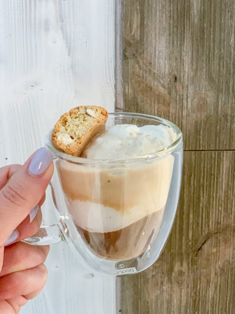 Holding up a finished affogato showing the layers of ice cream and espresso as it melts together. There's a biscotti on top.