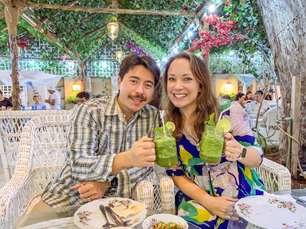 Pete and Rachelle at a restaurant in Dubai, toasting with mint lime smoothies.