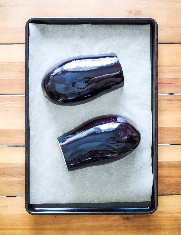Eggplant, cut in half, oiled, and face down on a parchment paper lined cookie sheet.