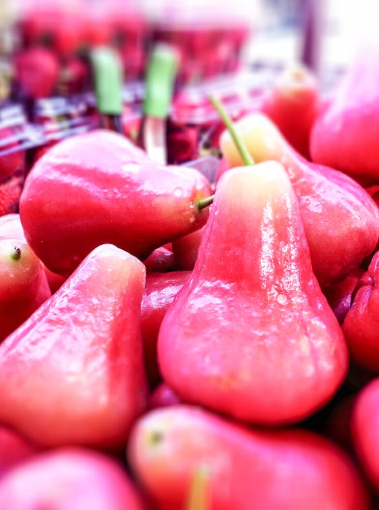 Pink Roseapples stacked at a farmer's market.