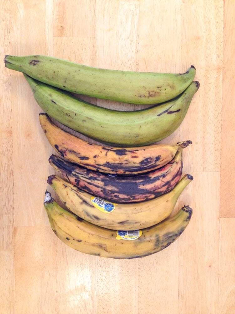 Six plantains showing varying degrees of ripeness, from green, to overripe, to yellow.