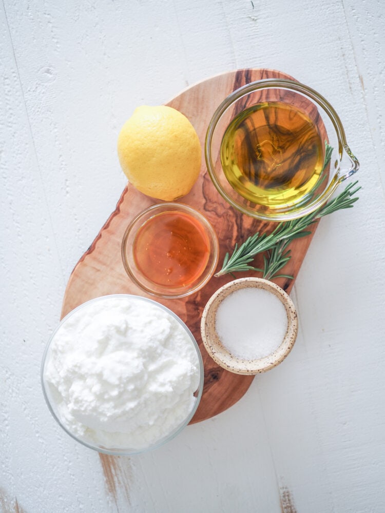 Overhead Shot Of Whipped Ricotta Dip Ingredients: ricotta cheese, honey, olive oil, salt, lemon, and sprigs of rosemary for topping.