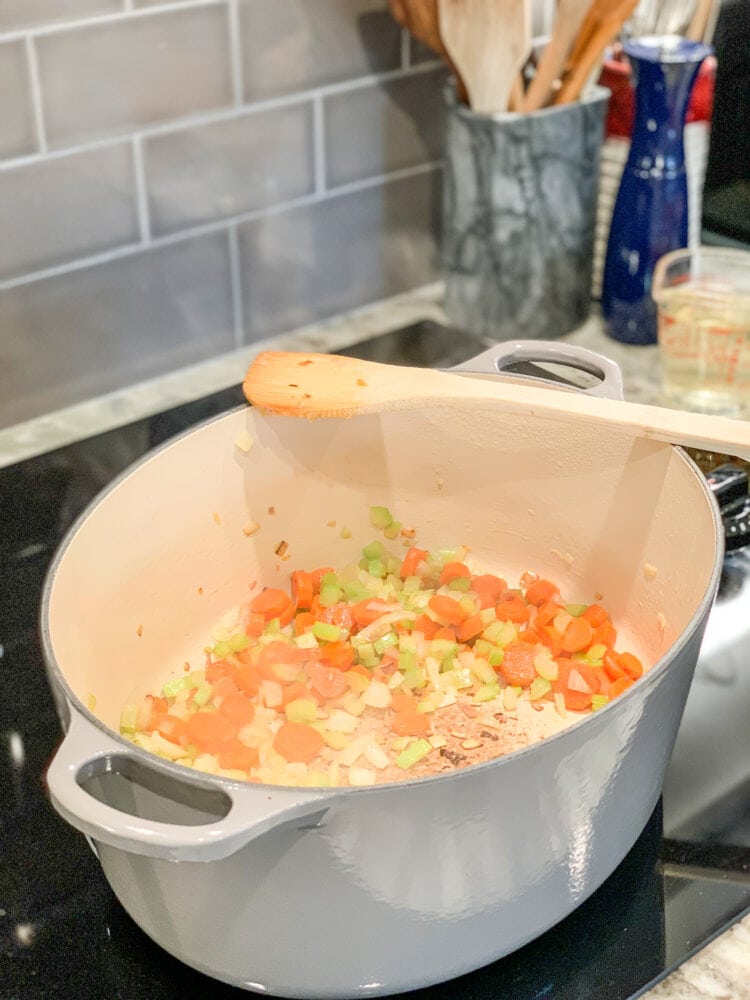 Simmering the carrots, shallots, and celery in a large cast iron pot.