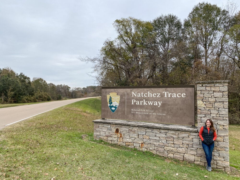 Rachelle standing next to the sign for the start of the Natchez Trace Parkway.