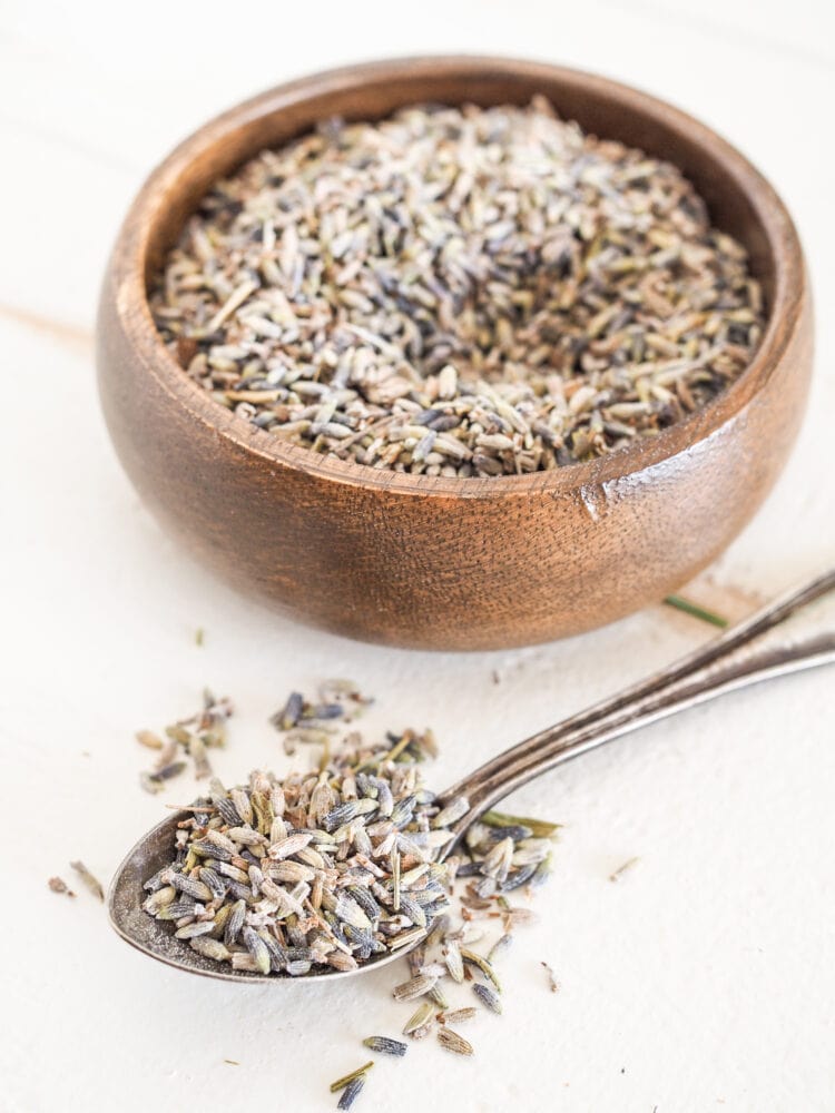 A small bowl and spoon filled with dried lavender buds.