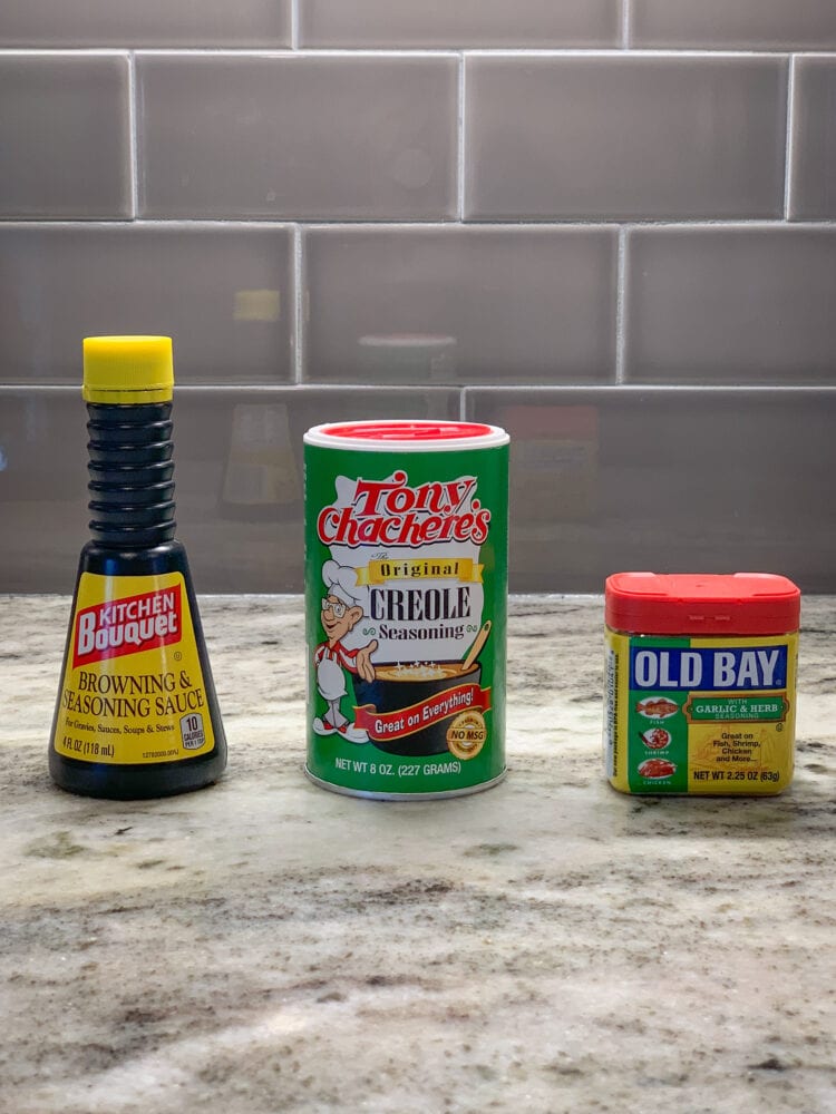 A photo of three different seasonings used for grits, Kitchen Bouquet, Tony Chachere's, and Old Bay.