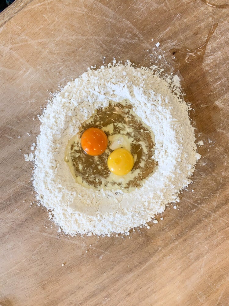Two eggs in the center of a pile of flour.