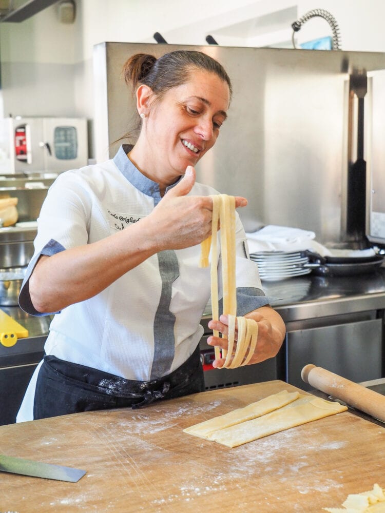 Carla holding up stands of fresh made tagliatelle.