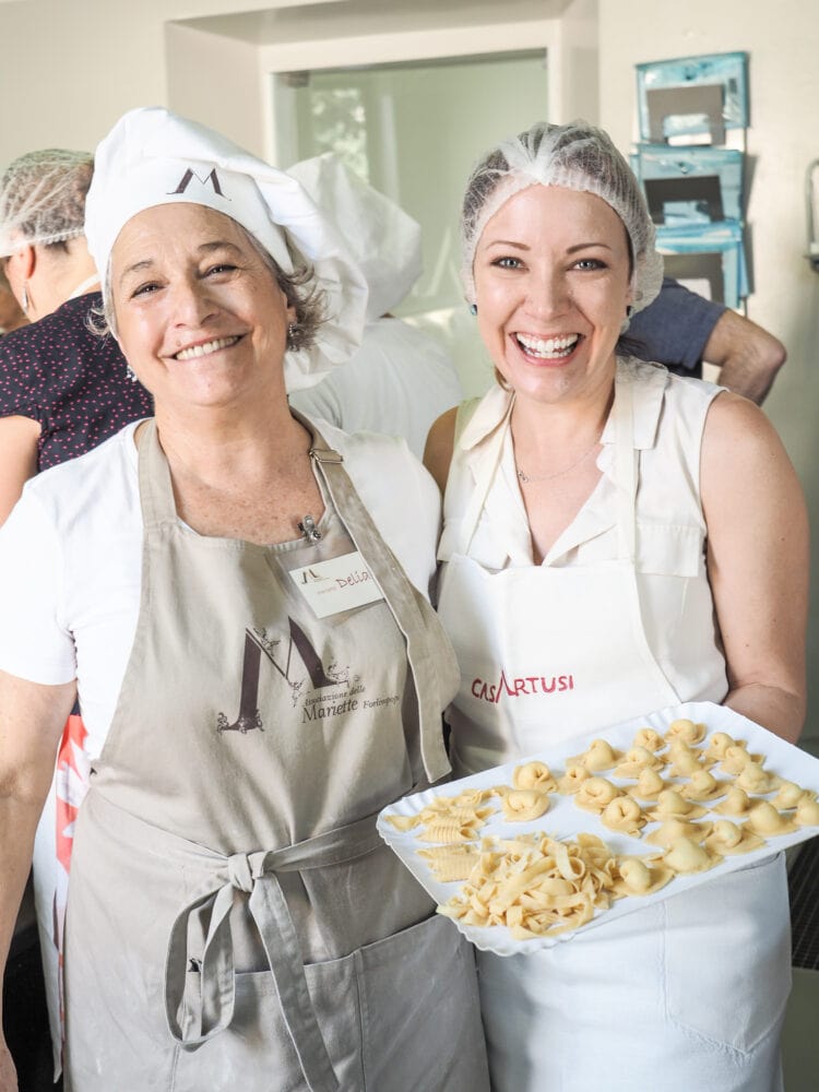 Delia and Rachelle smiling at the end of class while holding the finished pasta.