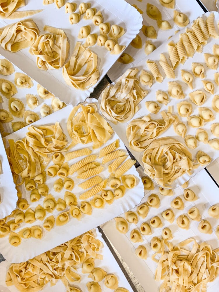 Paper plates holding different handmade pasta shapes.