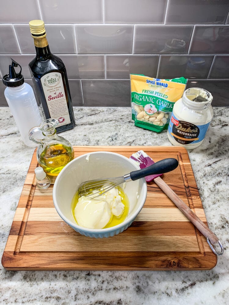 Making aioli, a bowl of mayonnaise and olive oil with garlic and squeeze bottle for serving in the background.