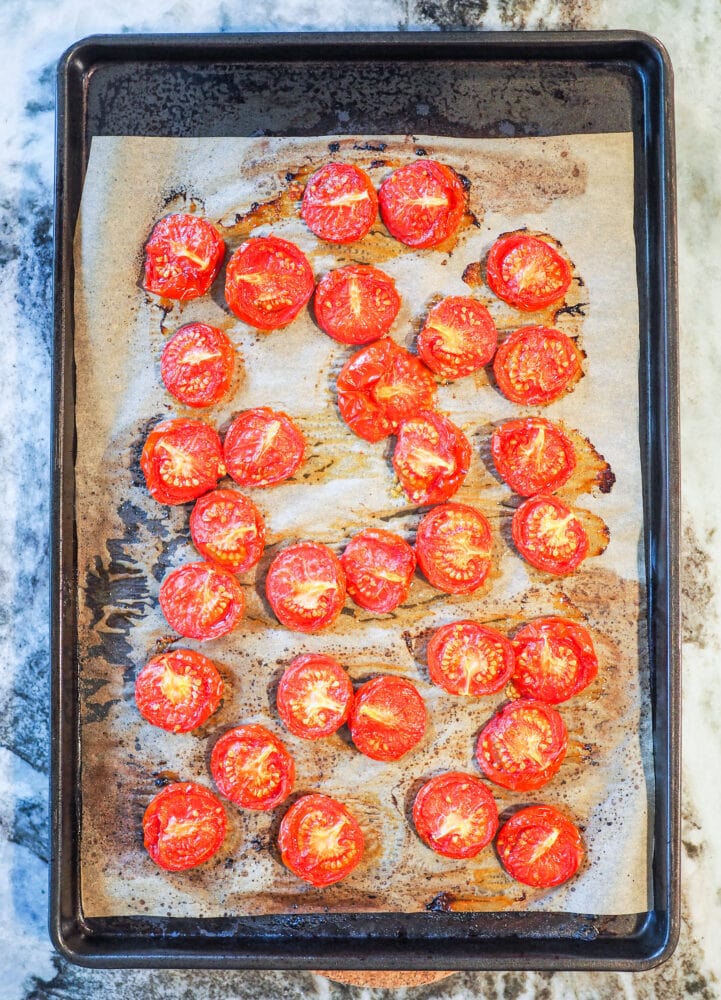 Overhead shot of sheet pan lined with parchment with oven roasted tomatoes.